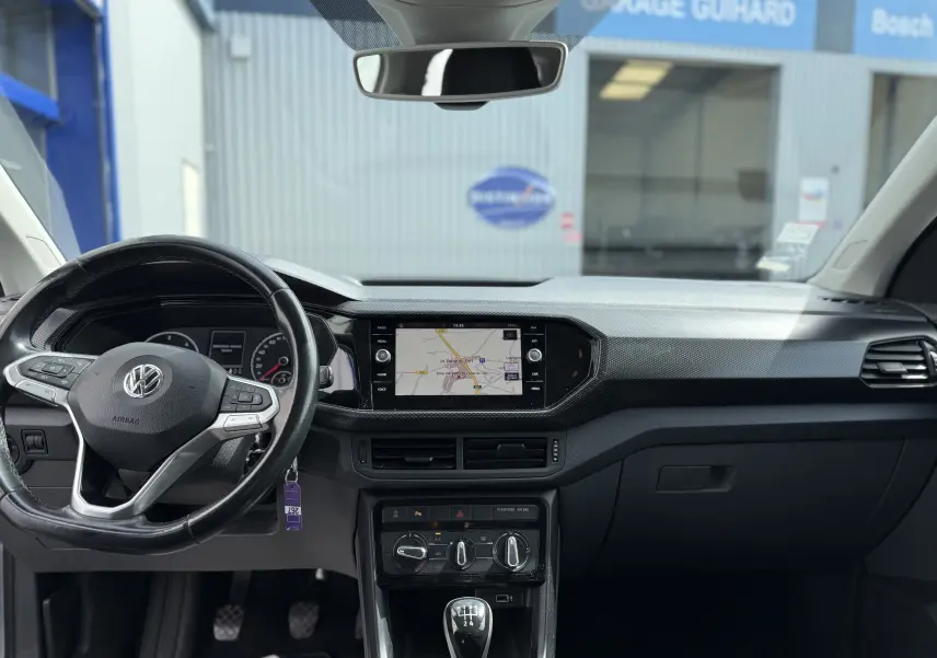 Vue intérieure avant du tableau de bord gris foncé du Volkswagen T-Cross 2019 avec volant multifonction et écran tactile central.