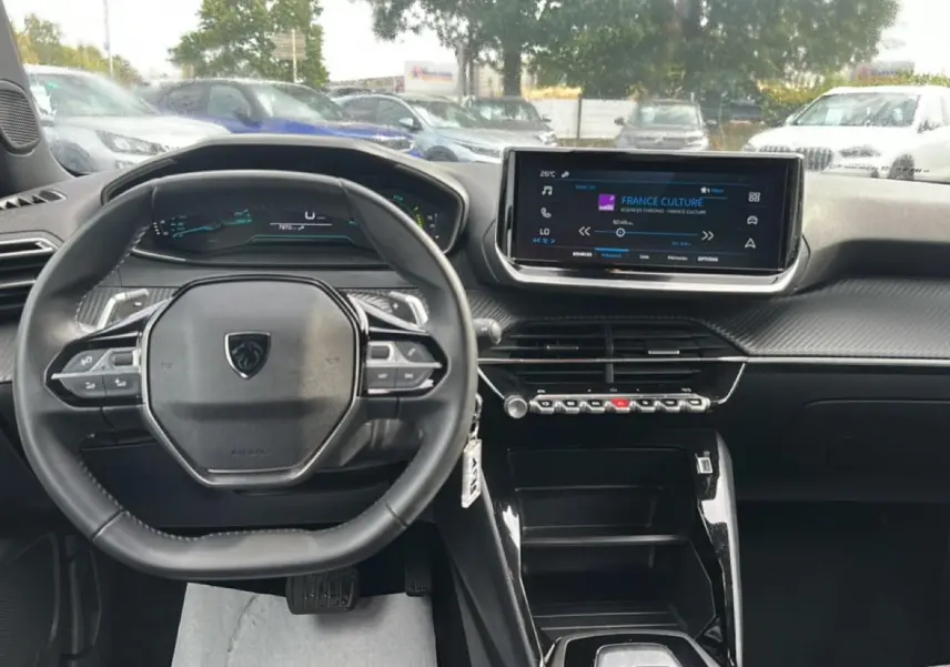 Vue intérieure frontale du tableau de bord du Peugeot 2008 gris, avec volant multifonction et écran tactile central allumé.