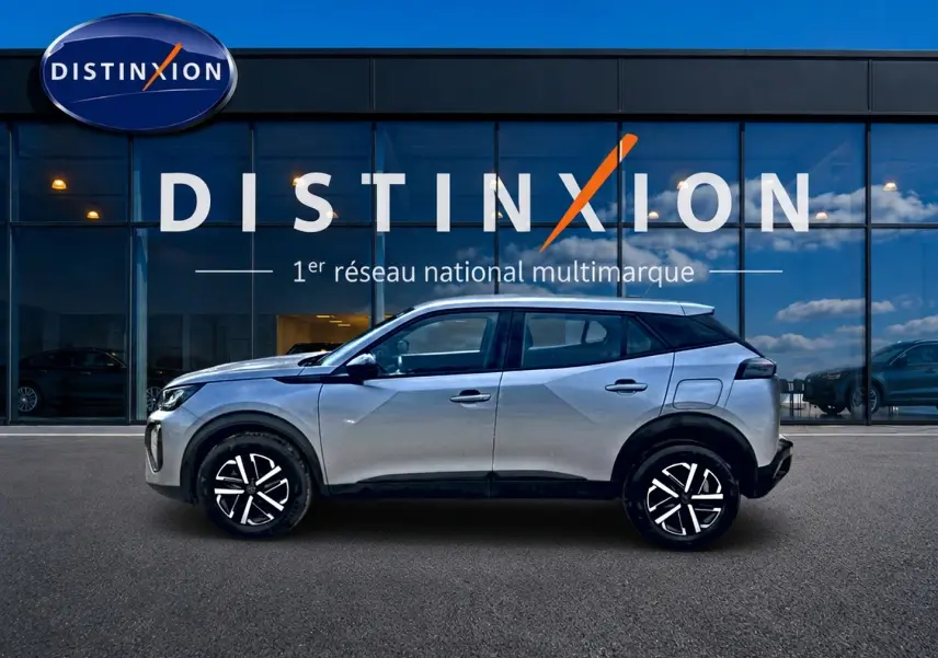 Peugeot 2008 gris en profil droit, avec jantes noires et toit noir, devant une vitrine Distinxion.