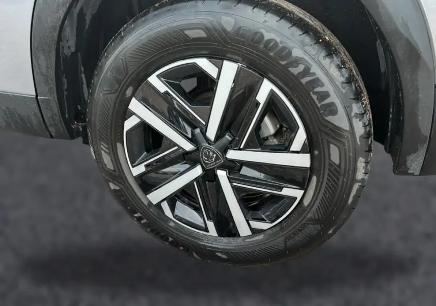 Gros plan sur la roue avant gauche du Peugeot 2008 gris, mettant en valeur la jante noire et argentée au design moderne.