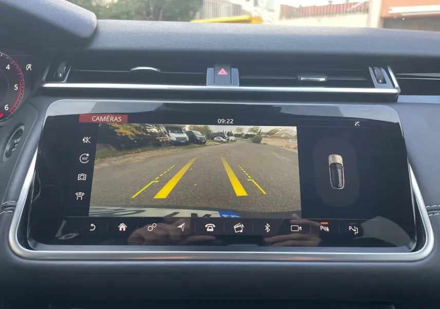 Écran central du Range Rover Velar 2019 montrant la caméra de recul avec lignes de guidage jaunes sur route grise.