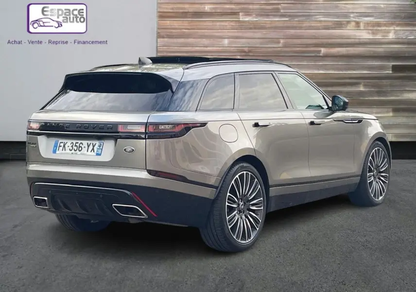 Vue 3/4 arrière droite d'un Range Rover Velar gris 2019 avec toit noir et jantes alliage distinctives.