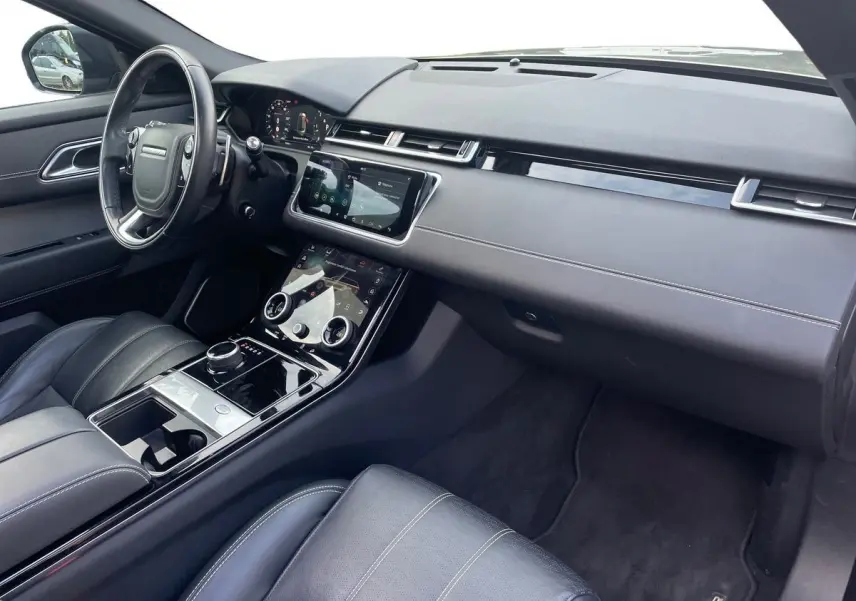 Intérieur noir du Range Rover Velar 2019, vue côté conducteur sur tableau de bord et console tactile moderne.