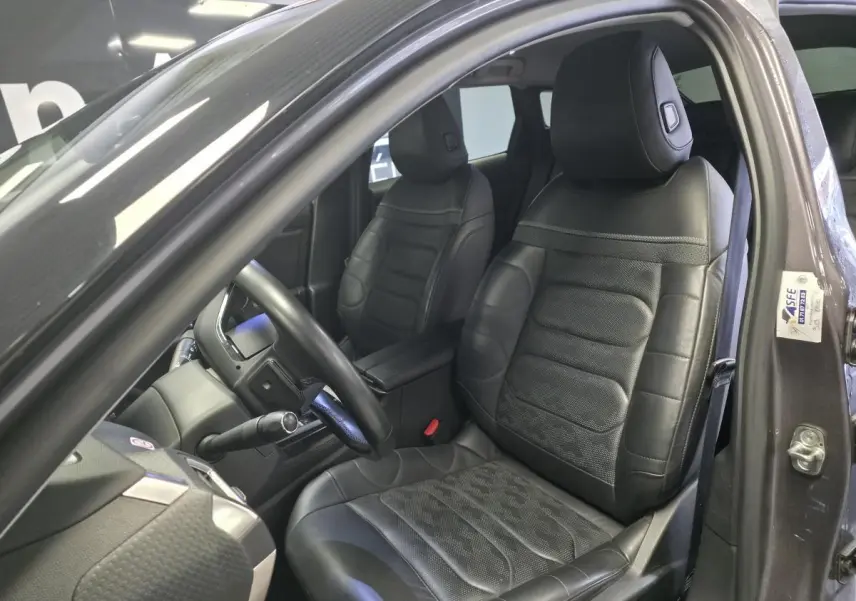 Intérieur de la Citroën C5 X hybride 2023, vue côté conducteur, sièges cuir noir perforé avec motifs chevron.