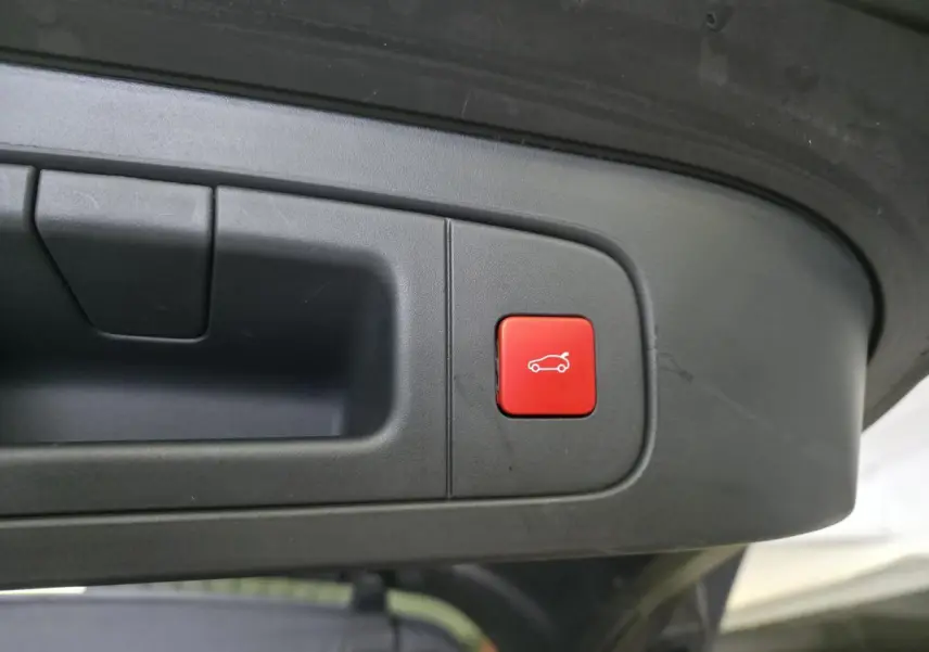 Gros plan sur le bouton rouge d'ouverture électrique du hayon du Citroën C5 X hybride rechargeable gris.