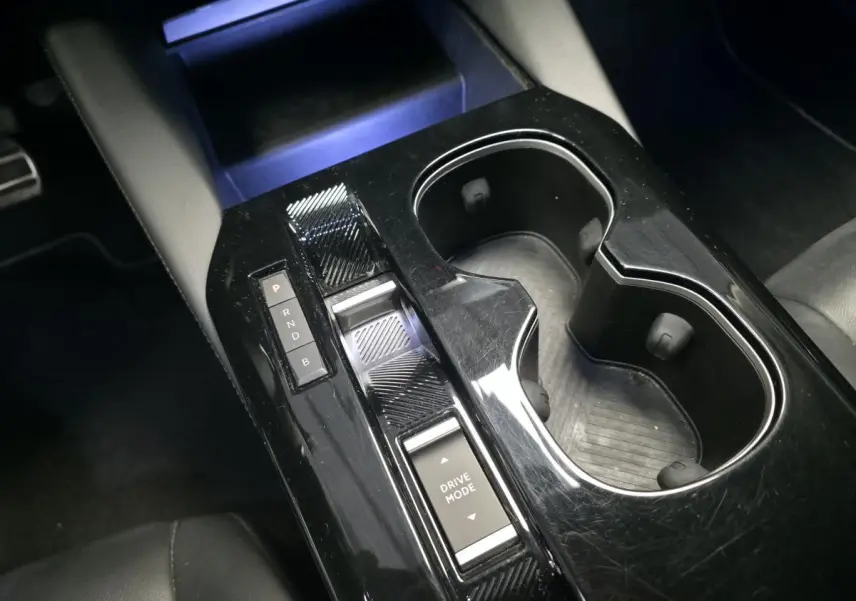 Console centrale noire brillante avec commandes de boîte automatique et porte-gobelets dans une Citroën C5 X Hybrid 2023.