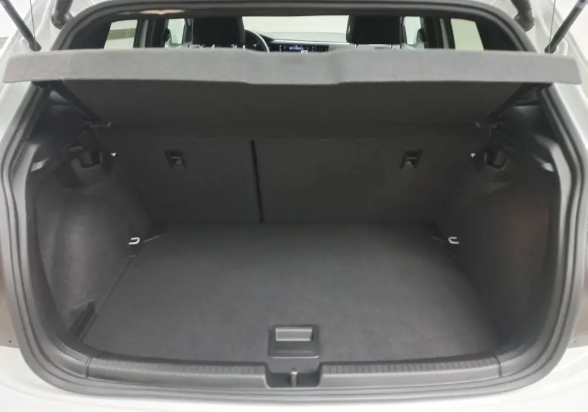 Coffre ouvert de la Volkswagen Polo blanc pur, vue arrière montrant l’espace de chargement et la tablette cache-bagages relevée.