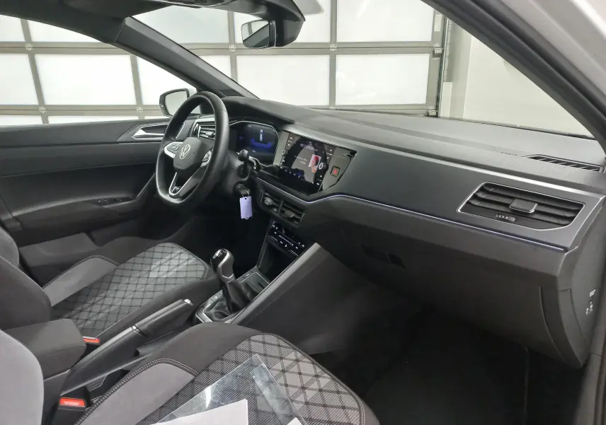 Intérieur avant droit de la Volkswagen Polo 1.0 TSI 95 BVM5 R-Line avec sièges tissu à motif, volant multifonction et écran tactile.