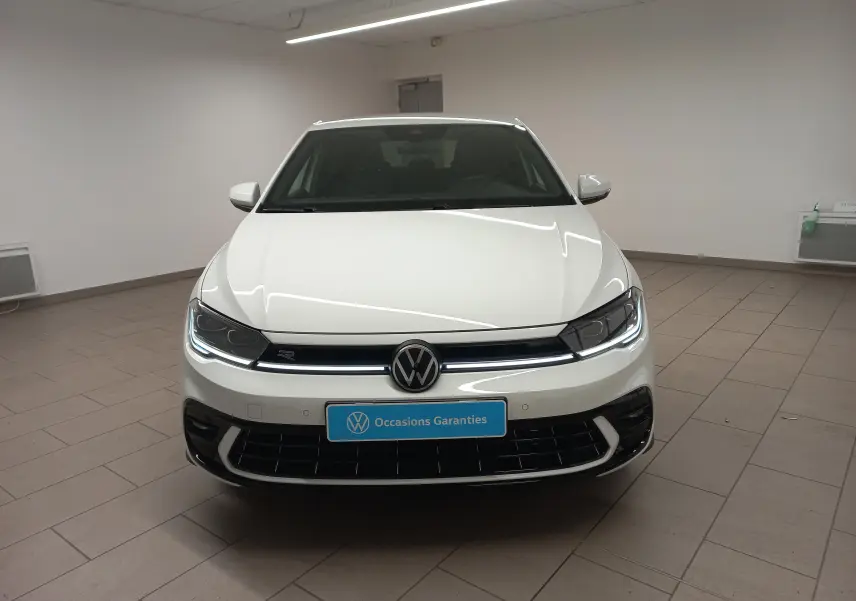 Vue avant d'une Volkswagen Polo 1.0 TSI R-Line blanche, avec phares LED allumés dans un intérieur neutre.