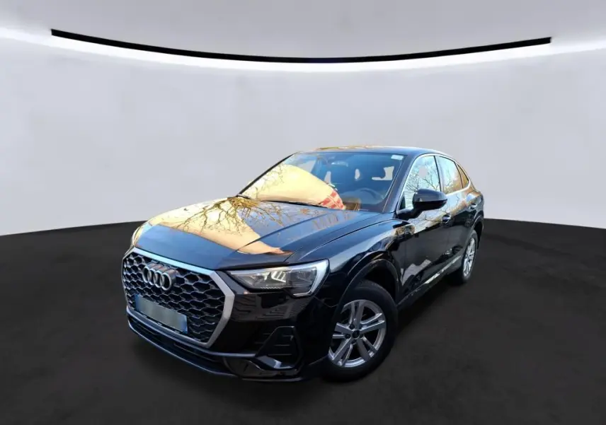 Audi Q3 Sportback noir vue 3/4 avant droit en intérieur, avec calandre hexagonale et jantes alu visibles.