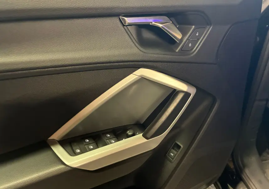 Gros plan sur la porte avant gauche noire de l'Audi Q3 Sportback 2022 avec commandes de vitres et verrouillage.