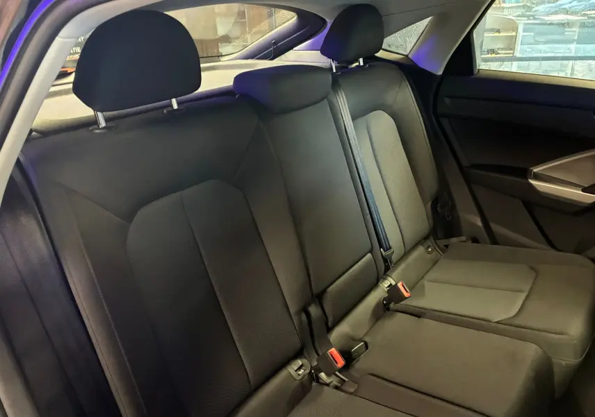Vue intérieure arrière côté droit de la banquette noire en tissu de l'Audi Q3 Sportback 2022 avec appuie-têtes et ceintures visibles.