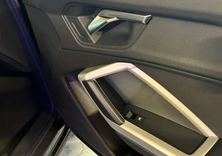 Vue rapprochée de la poignée intérieure côté gauche en plastique noir et argent de l'Audi Q3 Sportback 2022 noir.