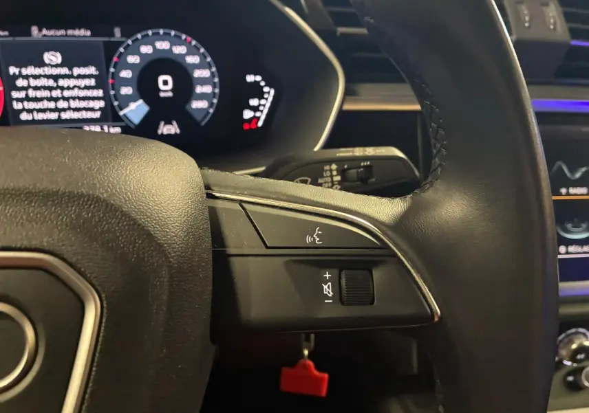 Gros plan sur le volant cuir multifonctions noir de l'Audi Q3 Sportback 2022 avec tableau de bord digital en arrière-plan.