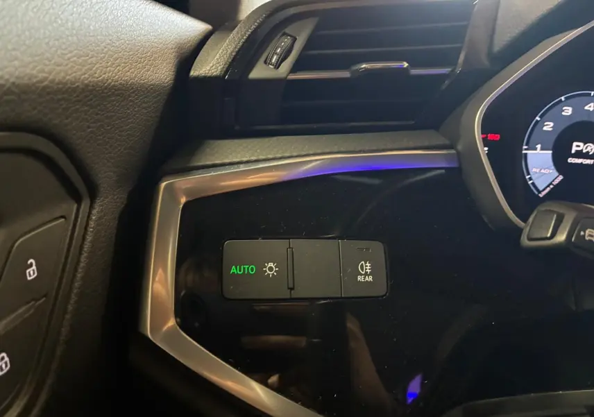 Gros plan sur les commandes d’éclairage automatiques dans l’habitacle noir de l’Audi Q3 Sportback 2022.