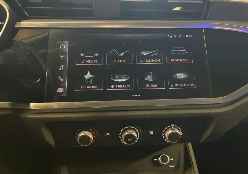 Vue rapprochée de l'écran tactile central et des commandes de climatisation de l'Audi Q3 Sportback noir 2022.