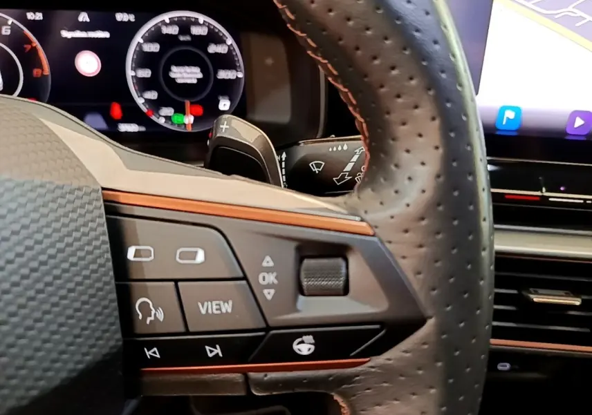 Gros plan sur le volant cuir perforé de la CUPRA Formentor 2022, avec commandes multifonctions et tableau de bord numérique.