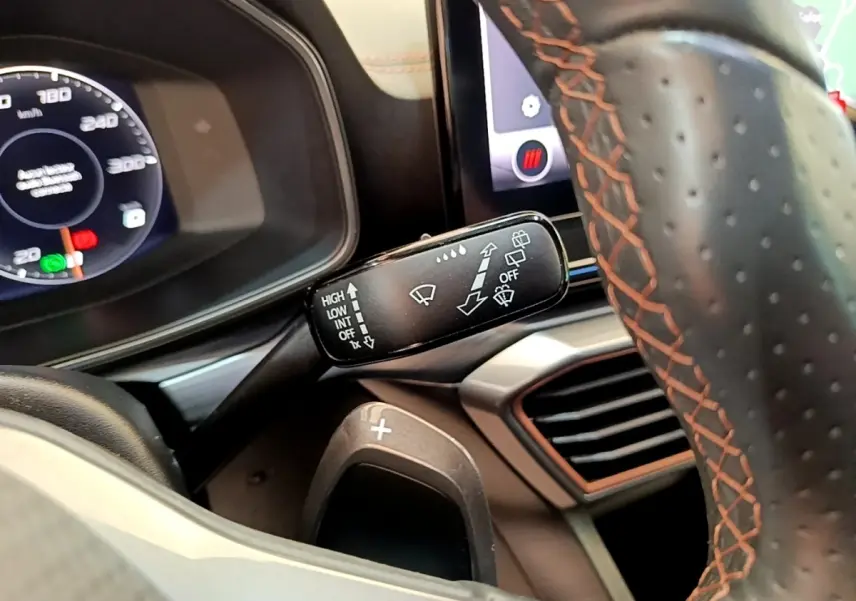 Gros plan sur le volant cuir gris foncé avec surpiqûres orange et commande essuie-glace du CUPRA Formentor 2022.