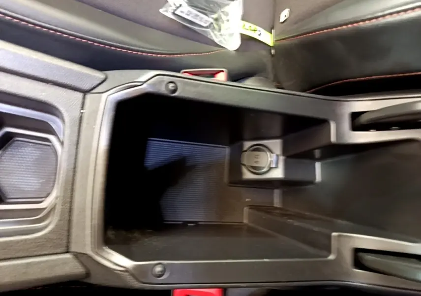 Vue rapprochée de la console centrale noire avec prise 12V et coutures rouges sur les sièges du CUPRA Formentor 2022.