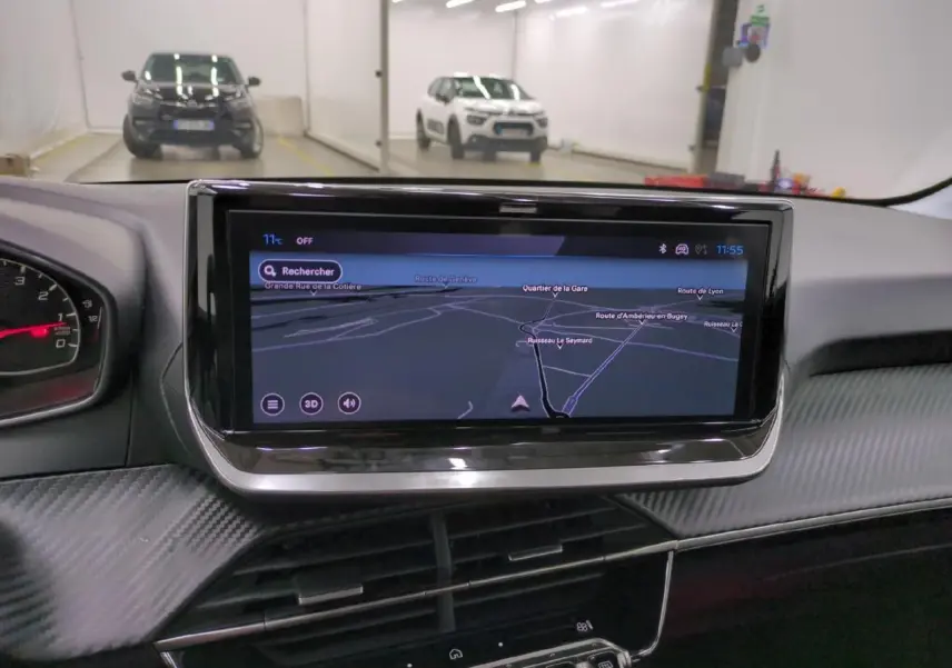 Vue intérieure centrée sur l'écran tactile 10'' du tableau de bord de la Peugeot 208 gris clair, avec navigation affichée.