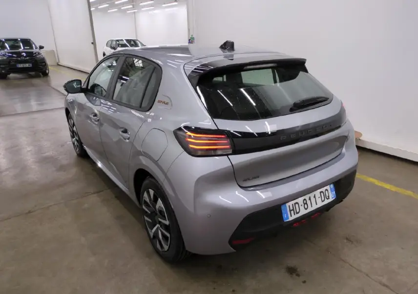 Vue 3/4 arrière droite d'une Peugeot 208 gris clair avec feux arrière à LED et bandeau noir brillant entre les feux.