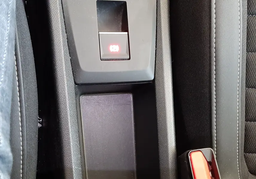 Gros plan sur la console centrale noire du Citroën C3 Aircross avec frein à main électronique et ceintures rouges.