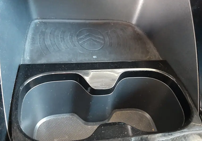 Gros plan sur le porte-gobelets et le chargeur sans fil avec logo Citroën, intérieur noir du C3 Aircross 2025.