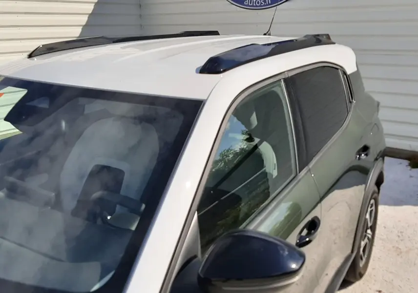 Vue 3/4 avant droit du Citroën C3 Aircross vert Montana avec toit blanc et barres de toit noires.