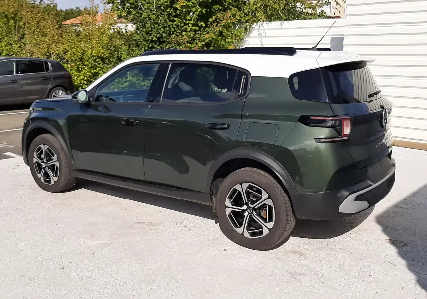 Vue 3/4 arrière droite d'une Citroën C3 Aircross 2025 vert Montana avec toit blanc et jantes biton.