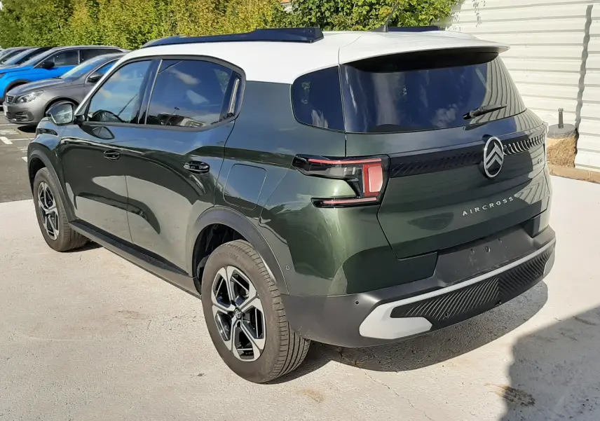 Vue 3/4 arrière droite d'une Citroën C3 Aircross 2025 vert Montana avec toit blanc et feux arrière LED distinctifs.