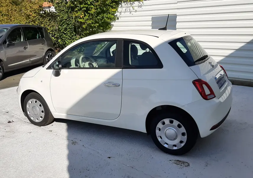 Fiat 500 blanche vue de profil côté gauche, compacte avec jantes acier et poignées chromées.