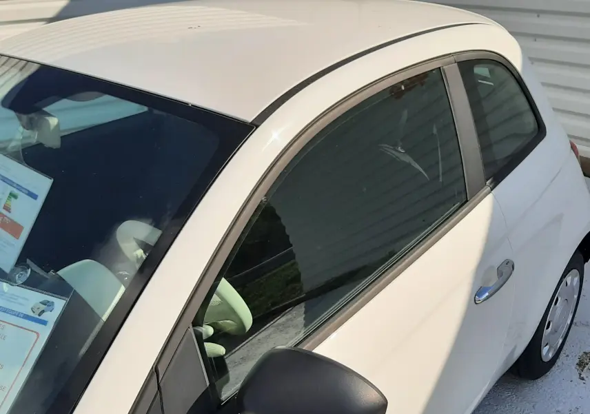 Vue de profil côté gauche d'une FIAT 500 blanche 2023 avec rétroviseur noir et carrosserie compacte.