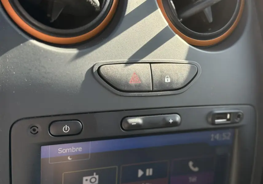 Détail du tableau de bord du Dacia Duster blanc Glacier 2017 montrant les commandes d'alerte et l'écran tactile GPS.