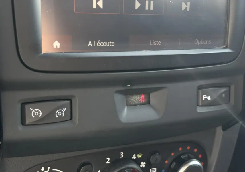 Gros plan sur la console centrale du Dacia Duster blanc, montrant les commandes de régulateur, alerte ceinture et radar de recul.