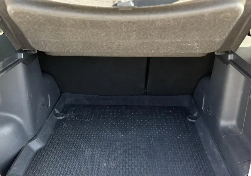 Coffre ouvert d'un Dacia Duster blanc glacier, montrant la surface de chargement avec tapis en caoutchouc noir.