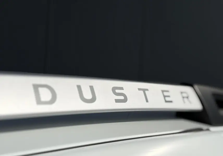 Gros plan sur la barre de toit blanche du Dacia Duster 2017 avec lettrage DUSTER visible en relief.