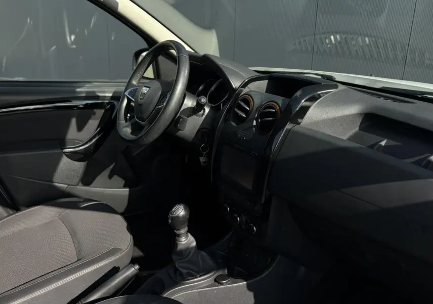 Intérieur du Dacia Duster TCE 125 Explorer 2017, vue côté conducteur, volant cuir et levier de vitesse manuel visibles.