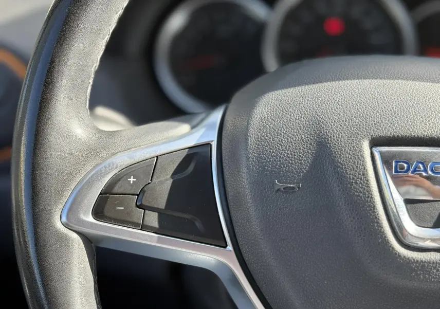 Gros plan sur le volant en cuir du Dacia Duster 2017, montrant les commandes de régulateur de vitesse à gauche.