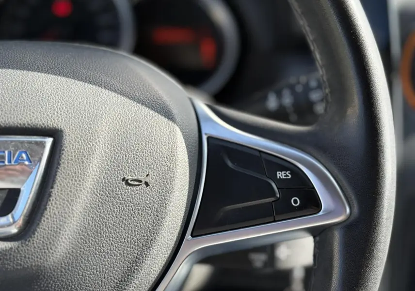 Gros plan sur le volant en cuir du Dacia Duster TCE 125 Explorer, avec commandes multifonctions visibles.