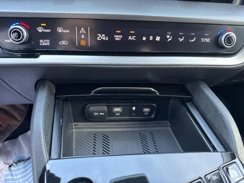 Détail de la console centrale du Kia Sportage 2022 avec commandes climatisation digitale et ports USB, 12V et recharge sans fil.