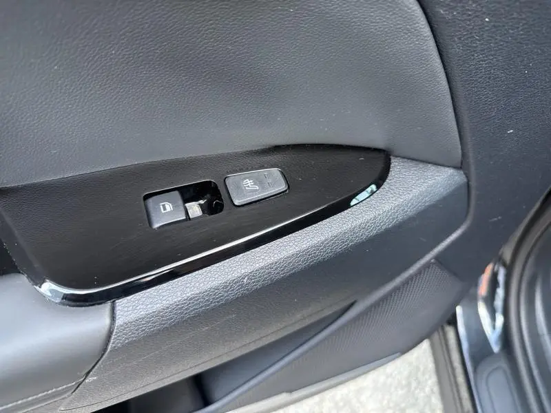 Gros plan sur les commandes de verrouillage et de chauffage des sièges sur la porte côté conducteur du KIA SPORTAGE noir Basalte.