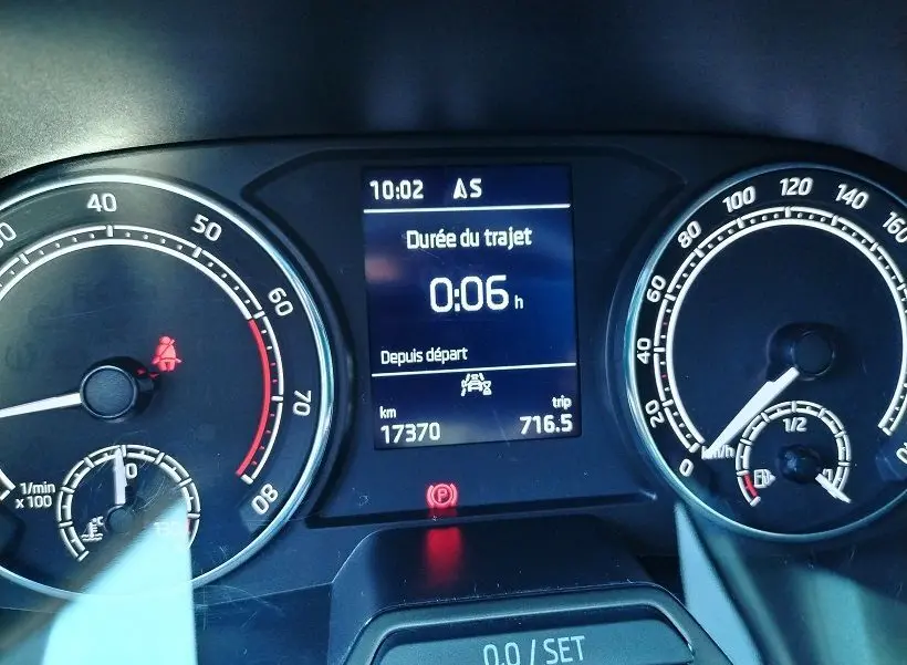 Vue rapprochée du tableau de bord de la Skoda Fabia blanche 2023, affichant la durée du trajet et compteurs analogiques.