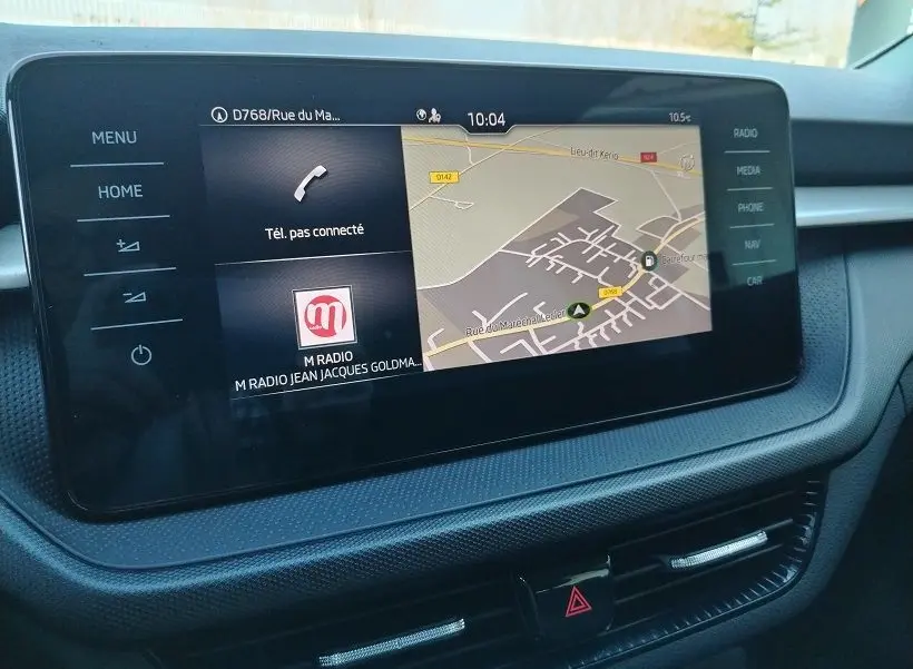Écran tactile central de la Skoda Fabia 2023 blanc, affichant navigation et options multimédia, vue intérieure frontale.