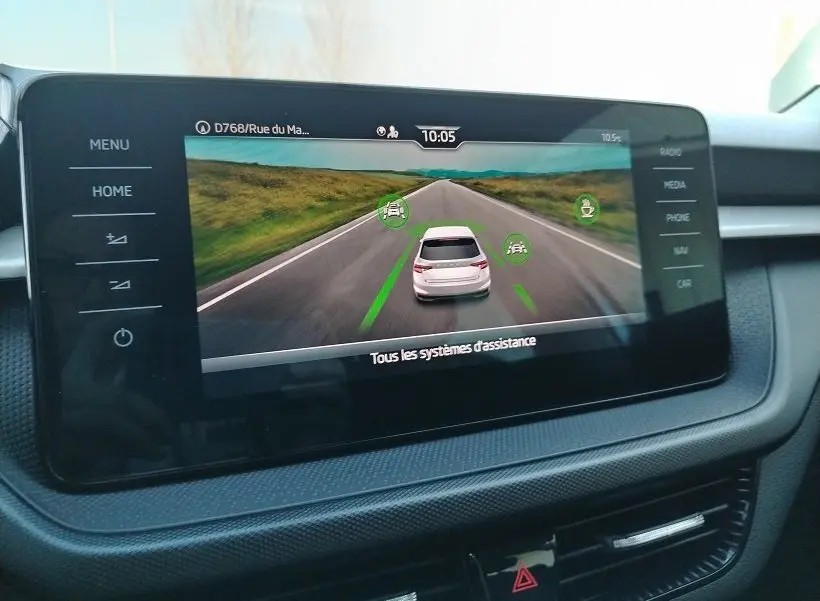 Écran central montrant l’assistance de conduite avec une Skoda Fabia blanche vue de l’arrière sur une route droite.