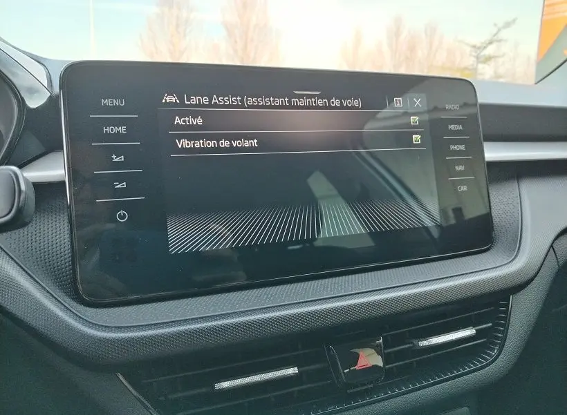 Écran tactile central de la Skoda Fabia 2023 affichant l'activation de l'assistant maintien de voie, intérieur noir.