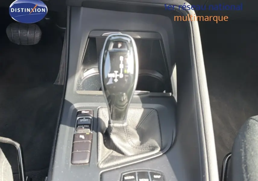 Gros plan sur le levier de vitesse automatique et les commandes de mode de conduite dans l’habitacle d’une BMW X1 blanche.