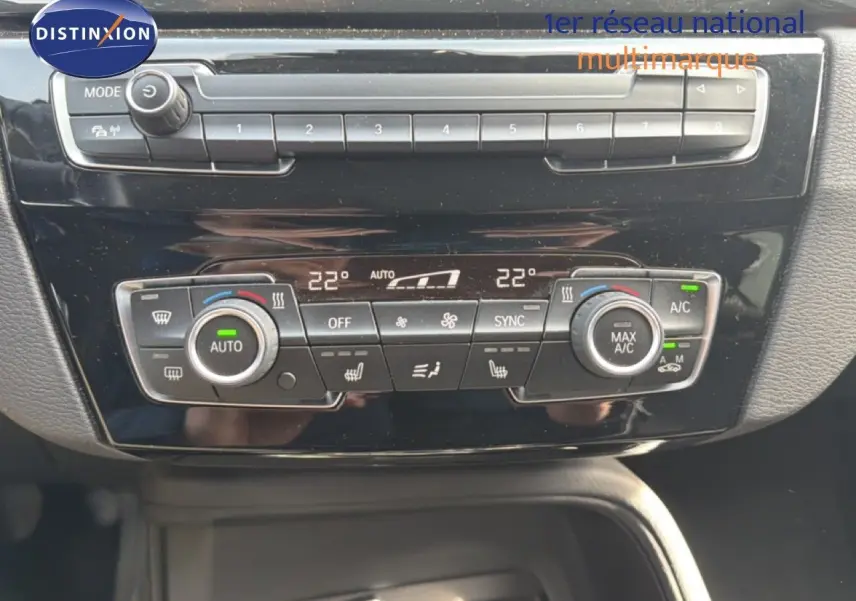 Tableau de bord de BMW X1 2022 en gros plan, montrant les commandes de climatisation automatique et les boutons multifonctions.