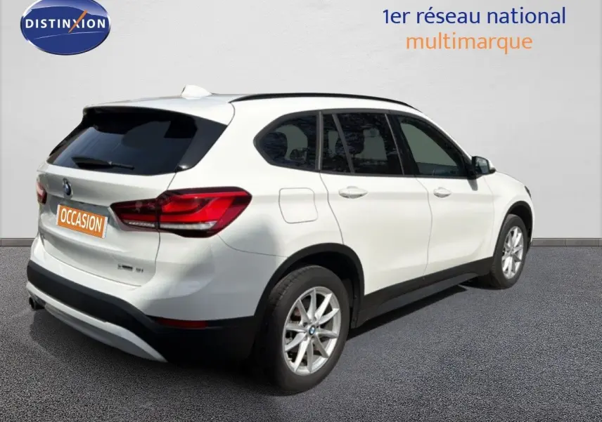 BMW X1 blanc vue 3/4 arrière côté droit, avec jantes alliage et feux arrière LED distinctifs.