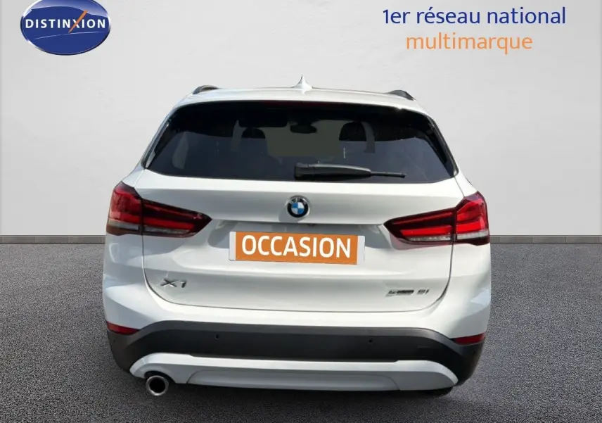 Vue arrière d'un BMW X1 blanc avec feux rouges et plaque "OCCASION" sur fond neutre.
