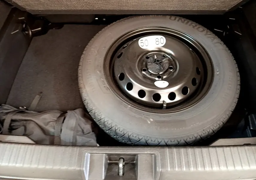 Vue plongeante sur la roue de secours noire dans le coffre du Renault Captur Zen E-Tech hybride gris foncé 2022.
